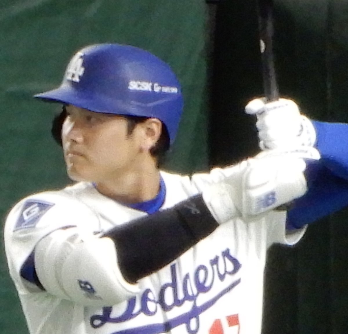Los Angeles Dodgers star Shohei Ohtani in the Dodgers white uniform and blue batting helmet, holding his bat before an at bat